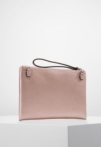 Clutch aus roségoldenem Leder mit strukturierter Oberfläche, Reißverschluss und abnehmbarem braunem Handgelenkriemen. Schlichte rechteckige Form.
