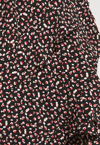 Tela negra con un patrón disperso de formas rojas, blancas y beige que parecen pequeños corazones, con un diseño texturizado y en capas.