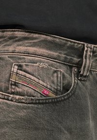 Γκρι τζιν από denim με φθαρμένη μπροστινή τσέπη, που διαθέτει ετικέτα "Diesel Industry" σε πράσινο και ροζ χρώμα και κλείσιμο με μεταλλικό κουμπί.