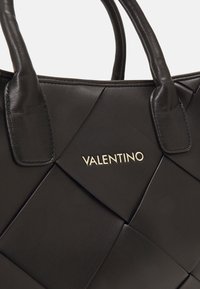 Svart läderhandväska med quiltat mönster och platta handtag. Har en gyllene "Valentino"-logotyp på framsidan för varumärkesidentifikation.
