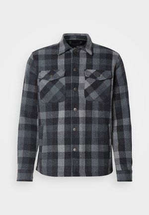 Camisa de hombre de mangas largas tipo chaqueta con patrón de cuadros en azul y gris, y dos bolsillos frontales con solapa y botones a presión.