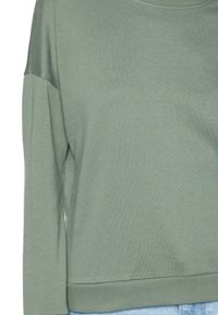 Sweat-shirt vert en tissu jersey doux ; présente un col rond, des manches longues et une coupe décontractée avec un ourlet et des poignets côtelés.