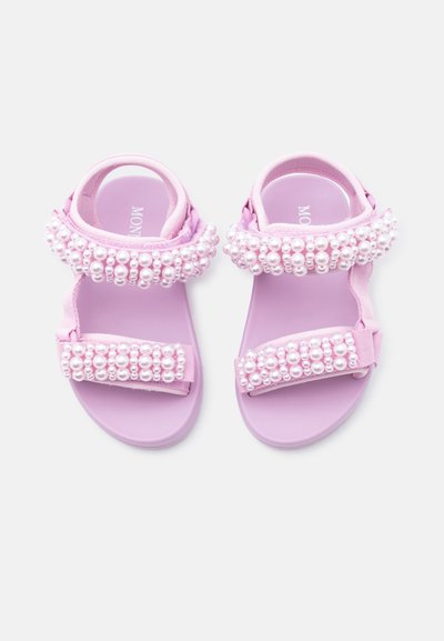 Λιλά σανδάλια με ρυθμιζόμενα λουριά διακοσμημένα με λευκές πέρλες, σχεδιασμένα για παιδιά, εμφανιζόμενα από πάνω σε λευκό φόντο.