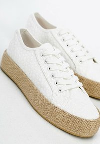 Weiße Canvas-Plattform-Sneaker mit gestickten Blumenmustern, weißen Schnürsenkeln und gewebten Jutesohlen für zusätzlichen Textur und Höhe.