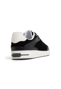 Czarne zamszowe i skórzane sneakersy z białymi akcentami, okrągłym noskiem, płaską podeszwą i detalem logo po bokach. Gumowa podeszwa zapewniająca przyczepność.