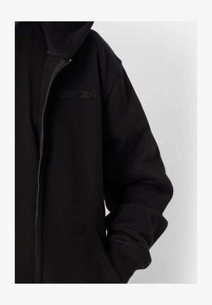 Sudadera con cremallera negra hecha de tela suave, con un bolsillo frontal, puños acanalados y "Sixth June" bordado en el pecho.