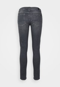 Jeans ajustados en denim gris oscuro, con bolsillos traseros con costuras curvas y una sutil textura desgastada, sin hardware o adornos visibles.