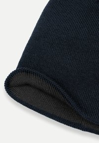 Tmavě modrá pletená zimní čepice s ohrnutým okrajem, který ukazuje šedou vnitřní podšívku na bílém pozadí.