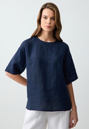 Top in lino blu navy con scollatura rotonda e maniche corte. Vestibilità ampia con una leggera texture e un design semplice.
