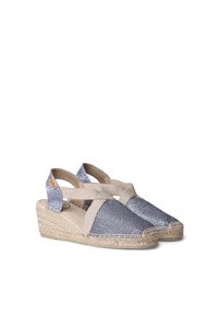 Espadrille wedge sandals with a silver woven upper, beige fabric straps, and a braided jute sole. Crossed strap design enhances stability.