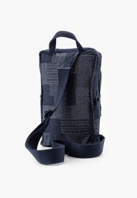 Borsa di stoffa blu navy con una texture a patchwork, chiusura con zip, tracolla regolabile e manico superiore per il trasporto. Presenta pannelli lisci e testurizzati.