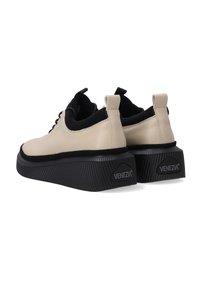 Beige Leder Schuhe mit schwarzen Akzenten, runder Spitze, flachen Schnürsenkeln und dicken schwarzen strukturierten Sohlen. Mit "VENEZIA" Branding an der Ferse.