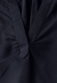 Tessuto blu navy con una consistenza morbida, caratterizzato da un collo a V, cuciture arricciate e dettagli di cucitura pulita lungo i bordi.