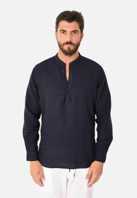Camicia in lino blu navy con colletto alla cinese, maniche lunghe e pattina con bottoni; presenta una vestibilità rilassata e una leggera texture.