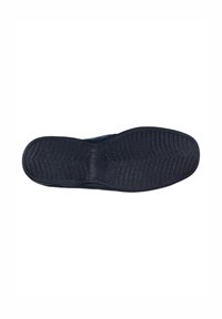 Suela de zapato de goma negra con un patrón texturizado, que incluye estrías y surcos para mejorar la tracción, y una zona central lisa.