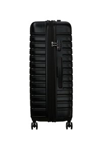 Valigia in policarbonato nera con superficie strutturata, righe verticali, lucchetto a combinazione e quattro ruote per la mobilità.