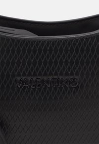 Svart gummisandaler med halkskydd som har ett strukturerat diamantmönster och den präglade "Valentino"-logotypen på den övre remmen.