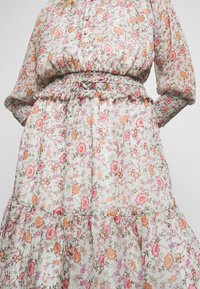 Sukienka w kwiatowy wzór wykonana z lekkiej, przejrzystej tkaniny. Zdobiona różowymi, pomarańczowymi i zielonymi kwiatami. Elastyczna talia z falbankami i plisą na guziki.