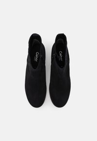 Stivaletti in camoscio nero dalla texture liscia, caratterizzati da un design slip-on e da cerniere laterali per una facile calzata. Linee minimaliste e pulite.