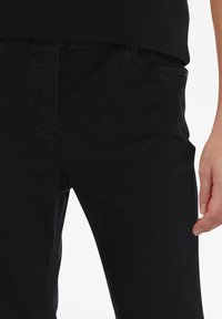 Zwarte denim jeans met een slim fit, voorzien van standaard zakken, subtiele stikdetails en een gladde textuur.