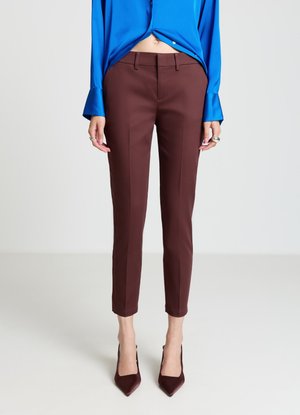Pantaloni marroni su misura con taglio aderente e lunghezza alla caviglia, caratterizzati da una texture liscia e da un dettaglio di piega sottile, abbinati a tacchi a punta.