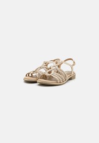 Sandali intrecciati di colore oro, con design open-toe, cinturino alla caviglia regolabile e suola piatta. Presenta un motivo intrecciato sulla parte superiore.
