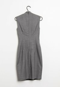 Ärmelloses graues Kleid aus strukturiertem Stoff, mit taillierter Passform, geradem Saum und vertikalen Nähten auf der Rückseite. Hängt an einem schwarzen Haken.
