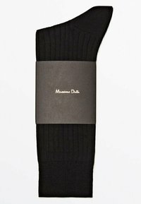 Sort ribbet knæhøje sokker med en glat tådel, pakket med en mørkegrå etiket, der viser "Massimo Dutti" i gyldne skrifttyper.