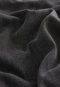 Close-up of soft, dark gray fabric with fine white thread patterns and gentle folds creating a textured, wavy surface.