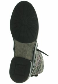 Suela de goma negra de una bota con una superficie texturizada y un patrón en relieve. Parte superior de tela decorativa multicolor con diseños intrincados.