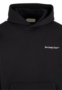 Sweat à capuche noir avec poche avant, capuche et texte blanc « Slow Sunday Club™ » sur la partie supérieure gauche de la poitrine.