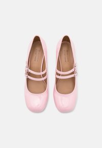 Ballet flats en cuir vegan rose avec des bretelles à double boucle et des orteils ronds. Texture lisse, design minimal.