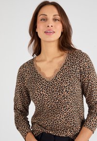 Bruine lange mouwen top met een luipaardprint en een scalloped V-halslijn. Zachte stof met een aansluitend ontwerp. Geen zichtbare logo's.