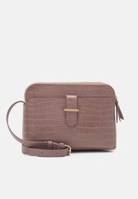 Laukku olalle mauve-värissä, krokotiilinaamioitu, kultaisilla soljilla, vetskareilla ja säädettävällä hihnalla valkoista taustaa vasten.