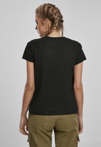 T-shirt noir à manches courtes avec un col rond, fabriqué en tissu doux, présentant une texture lisse et une coupe ajustée.