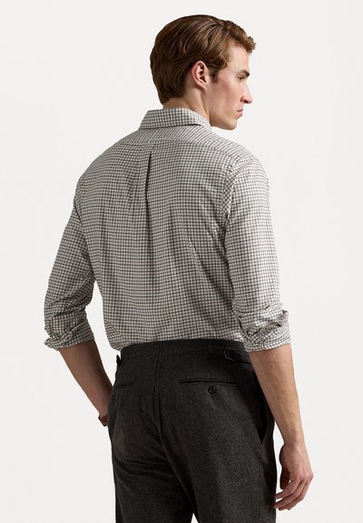 Rutete skjorte med knapper i hvitt, grått og svart med oppbrettede ermer. Kombinert med mørkegrå skreddersydde bukser med beltehemper og lommer.