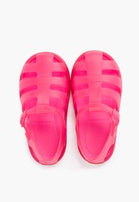 Bright pink waterproof sandals featuring an open design with adjustable straps and a textured sole for grip. Lightweight and breathable material.