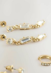 Orecchini in tono oro con cristalli chiari rettangolari e rotondi, caratterizzati da un design collegato e da un supporto per una vestibilità sicura. Include un ulteriore pezzo di orecchino.