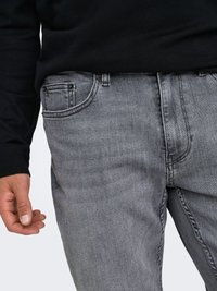 Jeans in denim grigio con vestibilità dritta, design a cinque tasche e passanti per cintura. Il tessuto ha una texture liscia e una finitura leggermente sbiadita.