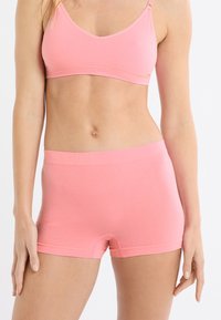 Bralette rosa chiaro con spalline sottili e un boyshort abbinato. Realizzato in tessuto morbido, presenta bordi senza cuciture e una cintura elastica.