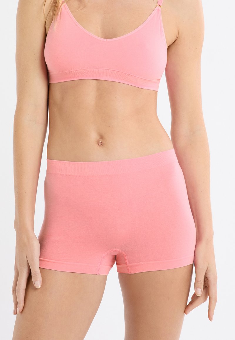 Bralette rosa chiaro con spalline sottili e un boyshort abbinato. Realizzato in tessuto morbido, presenta bordi senza cuciture e una cintura elastica.