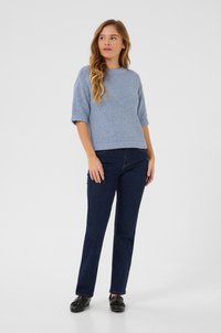 Pull en tricot bleu clair à manches courtes, associé à un jean droit bleu marine et des chaussures noires à enfiler. Design simple et texturé.