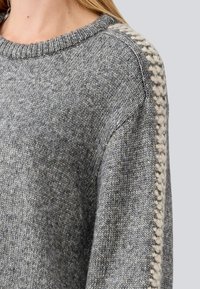 Gray knitted sweater featuring a ribbed crew neck and braided beige detailing along the shoulder seams. Soft texture, casual fit.