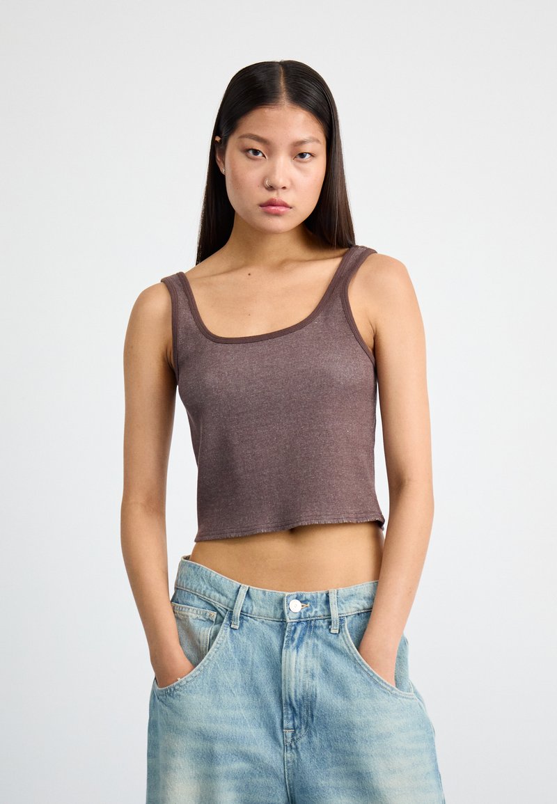 Top cropped castanho com textura canelada e alças largas, combinado com jeans de cintura alta azul claro com um corte relaxado.
