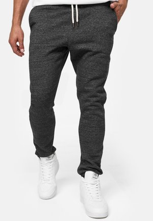 Joggers en coton gris au design ajusté, avec une taille à cordon de serrage et une texture subtile. Associés à des baskets blanches.