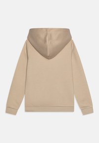 Bež hoodie s velikom, mekanom kapuljačom, dugim rukavima, rebrastim manžetama i pojasom. Tkanina se čini glatkom i udobnom s jednostavnim dizajnom.