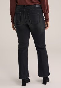 Jeans neri a vita alta con vestibilità slim, dotati di due tasche posteriori e un leggero effetto sbiadito, abbinati a scarpe nere con tacco.