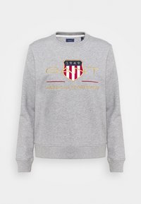 Grå sweatshirt lavet af blødt stof med lange ærmer, rund halsudskæring og ribkanter ved ærmerne. Har broderet logo med "1949" og "AMERICAN SPORTSWEAR."