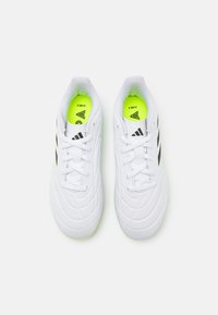 Zapatillas deportivas blancas con diseño texturizado, rayas negras y plantillas de un brillante verde neón. Tienen cordones y una forma de punta redonda.