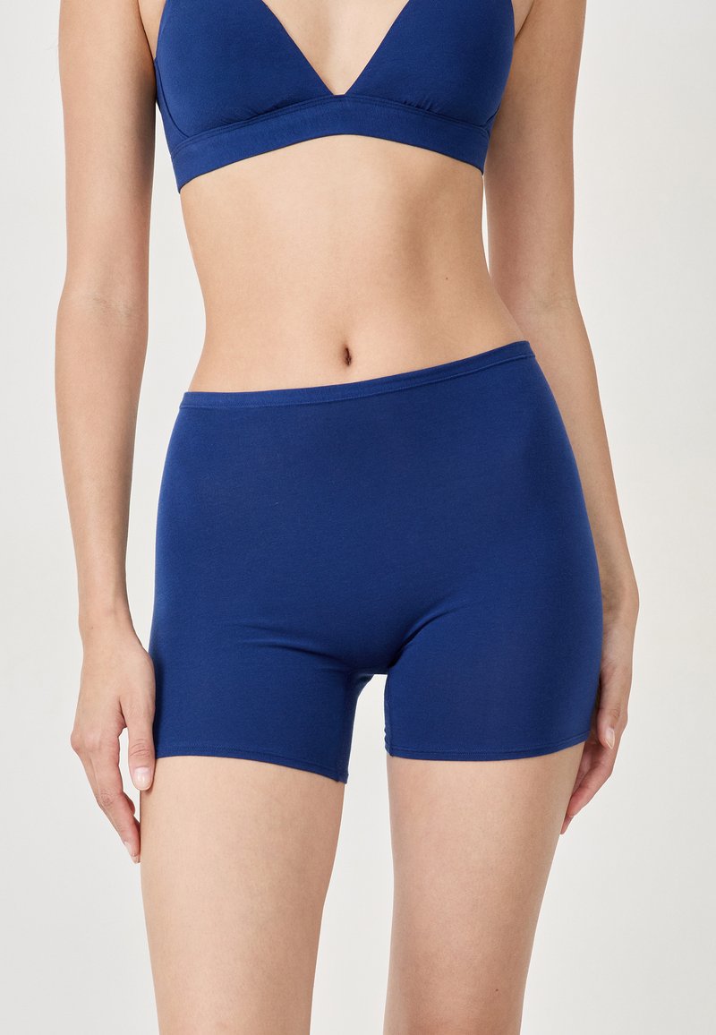 Shorts en tissu extensible bleu marine avec un design ajusté, longueur mi-thigh, et une taille élastique pour le confort et la liberté de mouvement.